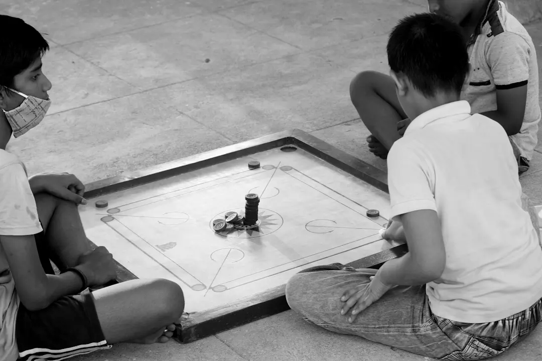 Kinder spielen gemeinsam Carrom an einem Board