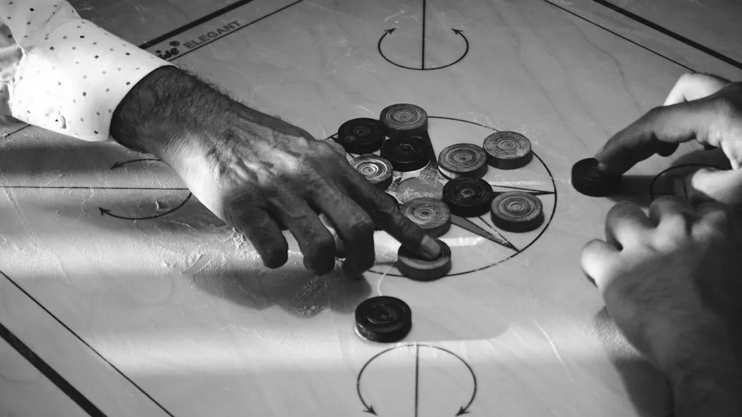 Zwei Personen spielen Carrom an einem Holzbrett
