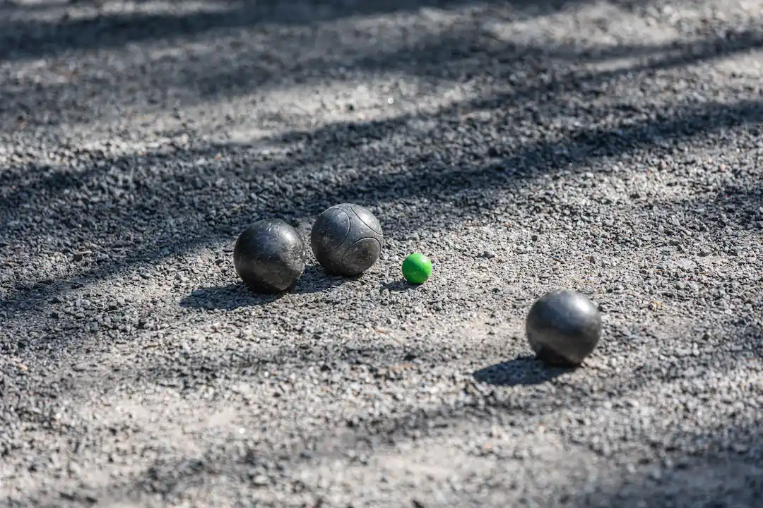 Pétanque Kugeln und Zielkugel auf Kies als Titelbild für die Boule und Pétanque Kaufberatung