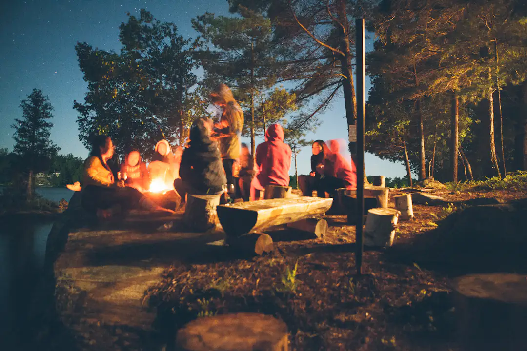 Erwachsene sitzen abends gemeinsam am Lagerfeuer auf einem Campingplatz