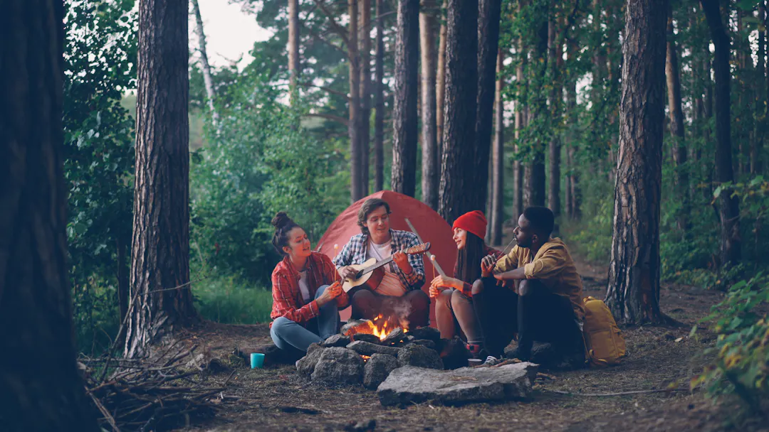 Freunde beim Camping im Wald mit Zelt und Tisch