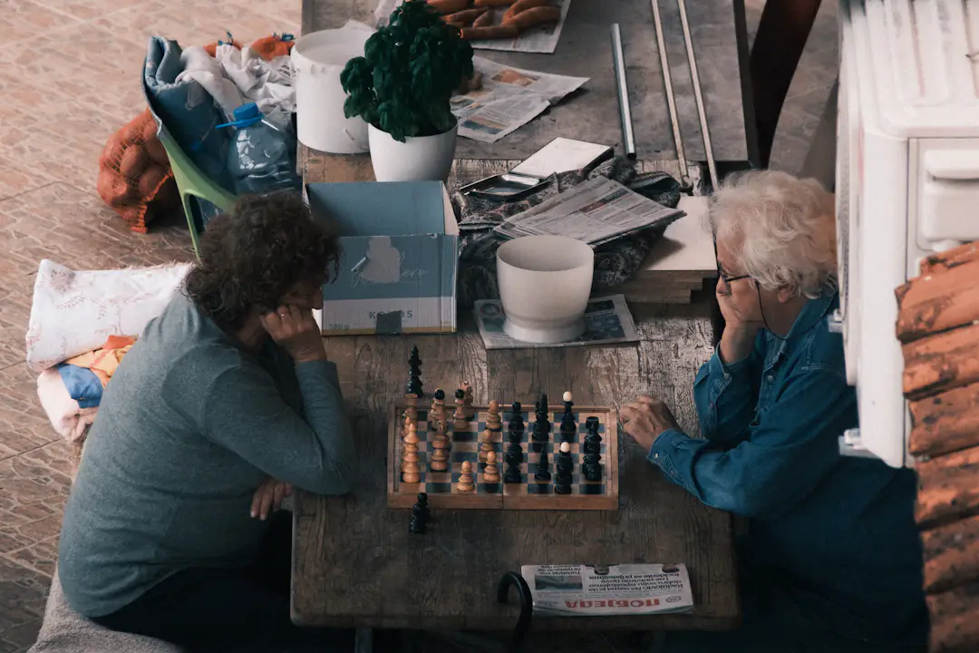 Älteres Paar spielt gemeinsam Schach an einem Holztisch