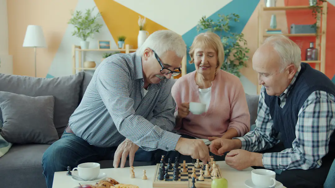 Ältere Freunde spielen gemeinsam Schach und trinken Tee