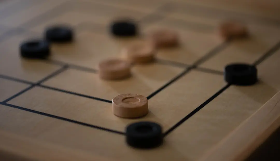 Holzspielsteine auf einem Strategiespiel als Motiv für Spiele ohne Glück und Zufall