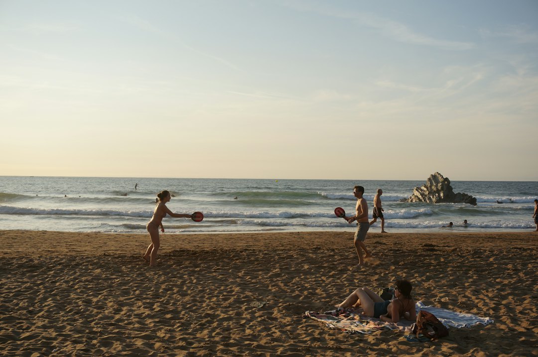 Zwei Menschen spielen Paddleball an einem Sandstrand