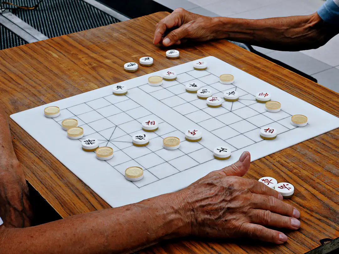 Zwei Personen spielen ein Strategiespiel am Tisch als Motiv für Tischspiele für zwei Personen